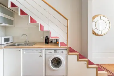 a kitchen with a washing machine and a staircase at GuestReady - Bright Apartment near Bolhão in Porto