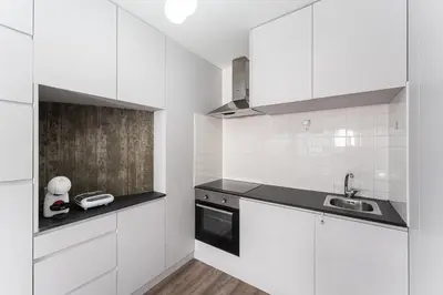 a white kitchen with white cabinets and a sink at GuestReady - Grayscale in Porto