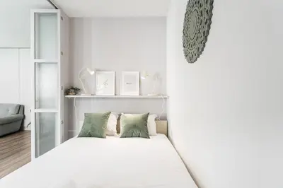 a white bedroom with a white bed with green pillows at GuestReady - Grayscale in Porto