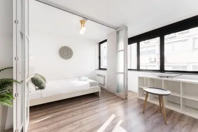 a white bedroom with a bed and a stool at GuestReady - Grayscale in Porto