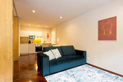 a living room with a blue couch and a kitchen at Aposentus - Your home in Porto in Porto