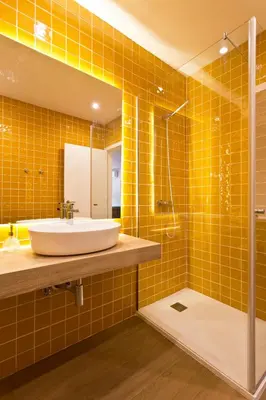 a bathroom with a sink and a shower with yellow tiles at Aposentus - Your home in Porto in Porto