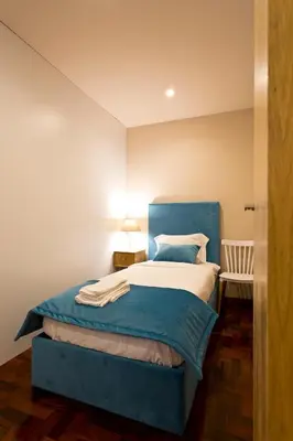 a bed with a blue headboard in a room at Aposentus - Your home in Porto in Porto