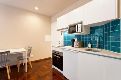 a kitchen with white cabinets and blue tiles at Aposentus - Your home in Porto in Porto