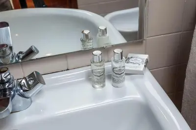 a bathroom sink with two bottles of soap and a mirror at Le Chien Noir City Centre in Porto