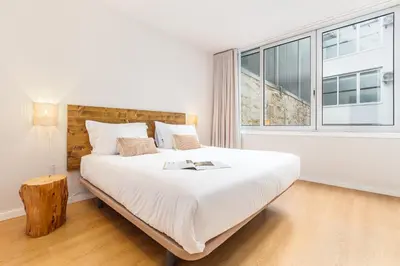 a white bedroom with a large bed and a window at Dream On - Almada Lofts in Porto