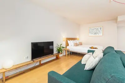 a living room with a green couch and a flat screen tv at Dream On - Almada Lofts in Porto