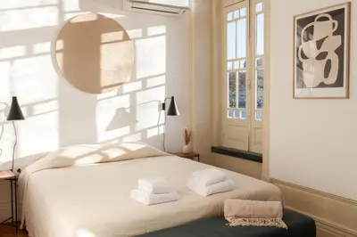 a bedroom with a white bed with towels on it at VIVA Alameda Suites - River Guest House in Porto