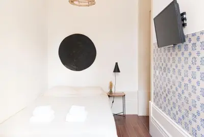 a bedroom with a bed and a tv on the wall at VIVA Alameda Suites - River Guest House in Porto