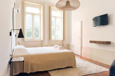 a bedroom with a bed and a flat screen tv at VIVA Alameda Suites - River Guest House in Porto