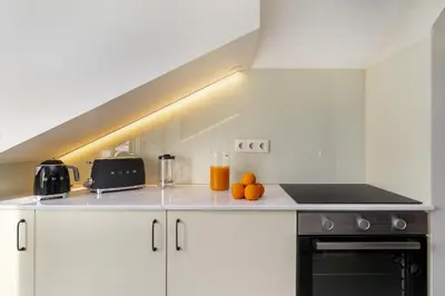 a kitchen with white cabinets and a stove top oven at Douro Prestige Urban Retreat with shared S-Pool & Gym in Porto