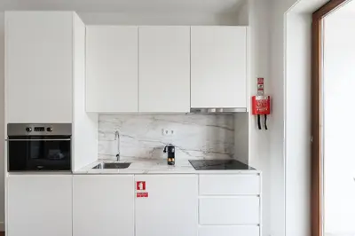 a white kitchen with white cabinets and a sink at GuestReady - Almada 516 in Porto