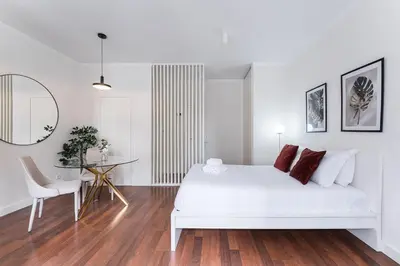 a white bedroom with a white bed and a table at GuestReady - Almada 516 in Porto