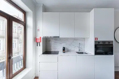 a white kitchen with a sink and a window at GuestReady - Almada 516 in Porto