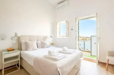 a white bedroom with a bed and a balcony at GuestReady - Port Studio 4 in Vila Nova de Gaia
