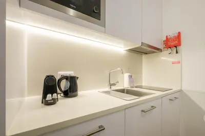 a white kitchen with a sink and a microwave at GuestReady - Port Studio 4 in Vila Nova de Gaia