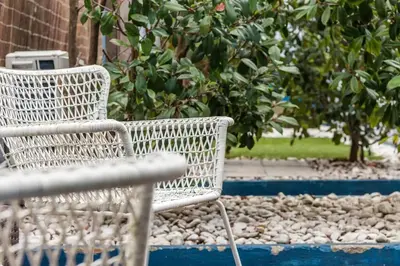 a white wicker chair sitting next to a bush at InLapa Studio V Porto Terrace in Porto