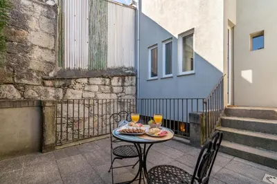 a table with two glasses of orange juice on a balcony at Host Wise - Sweet Bright Flats - City Center in Porto