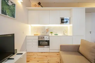 a small kitchen with white cabinets and a couch at Charming T2 by Indulge Porto Flats in Porto