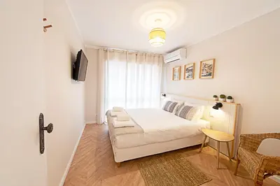 a white bedroom with a bed and a chair at CityLiving in Porto
