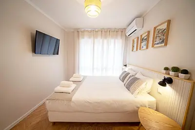 a bedroom with a bed with white sheets and a window at CityLiving in Porto