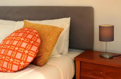 a bed with an orange and white pillow and a table at Villa Invicta 3 in Porto