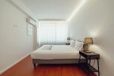 a white bedroom with a bed and a table at Grand Premium Boavista Apartment by Vacationy in Porto