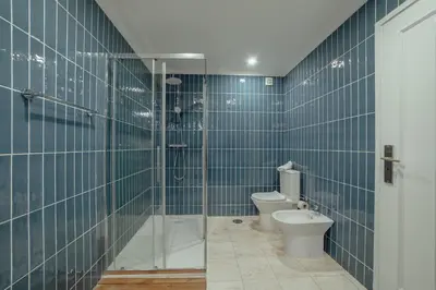 a blue tiled bathroom with a toilet and a shower at Grand Premium Boavista Apartment by Vacationy in Porto