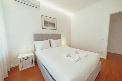a white bedroom with a bed with two trays on it at Grand Premium Boavista Apartment by Vacationy in Porto