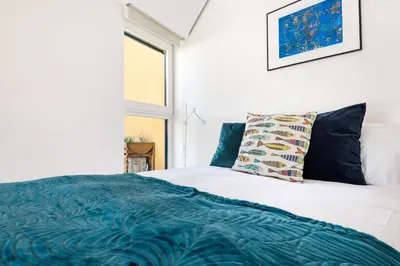 a white bed with a blue blanket and a window at Casa Flora in Porto