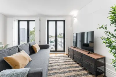 a living room with a gray couch and a flat screen tv at Sunshine Luxury House Urban Retreat Downtown Porto in Porto