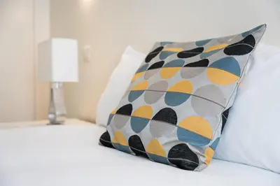 a pillow sitting on a bed next to a lamp at GuestReady - Enigma Apartments in Porto