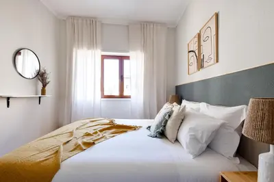 a bedroom with a large bed with white sheets and pillows at Trendy and Modern 3BR Family Home in Porto