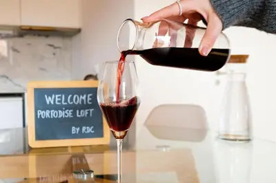 a person pouring red wine into a wine glass at PortoDise Loft by RDC in Porto