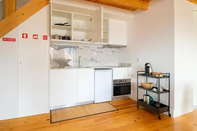 a kitchen with white cabinets and a wooden floor at PortoDise Loft by RDC in Porto