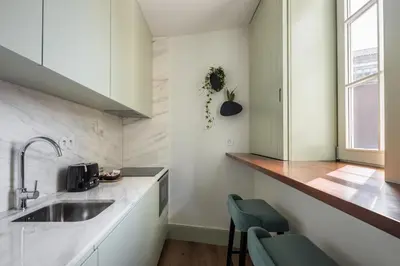 a kitchen with a sink and two green chairs at ORM Portas Santa Catarina Apartments in Porto
