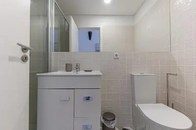 a white bathroom with a toilet and a sink at Lovely Bonfim in Porto