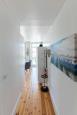 a hallway with white walls and wooden floors and a painting on the wall at Lovely Bonfim in Porto