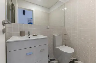 a white bathroom with a toilet and a sink at Lovely Bonfim in Porto