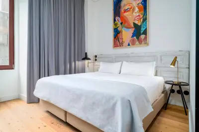 a bedroom with a white bed with a painting on the wall at Limehome Porto Rua Das Oliveiras in Porto