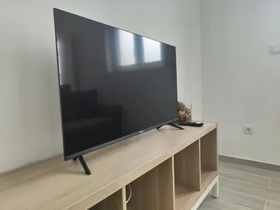 a large flat screen tv sitting on a wooden stand at Casa Mini-Ventuzelo by JC in Porto