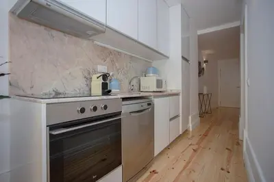 a kitchen with white cabinets and a stove top oven at Liiiving in Porto - Clérigos Terrace Apartment in Porto