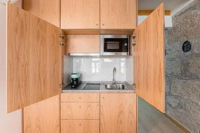 a kitchen with wooden cabinets and a sink at GuestReady - Miragaia Stone Studios & Apartments in Porto