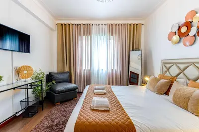 a bedroom with a large bed and a chair at Casa da Música Guesthouse in Porto