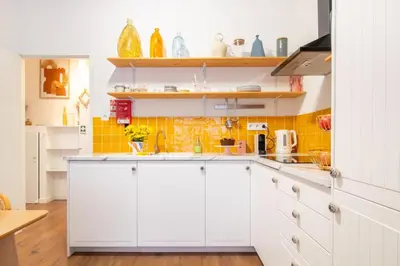a kitchen with white cabinets and yellow tiles at Campinho 1T - Stylish 1BR by LovelyStay in Porto