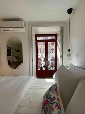 a bedroom with a white bed and a mirror at Historic Porto Balcony Hideaway - Taipas House 60 in Porto