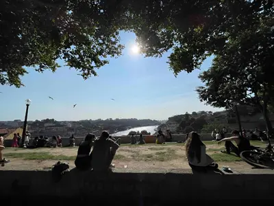 a group of people sitting on the grass near a river at Historic Porto Balcony Hideaway - Taipas House 60 in Porto