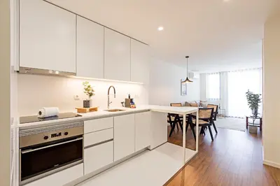 a kitchen with white cabinets and a dining room at Santos Pousada 1071 by LovelyStay in Porto